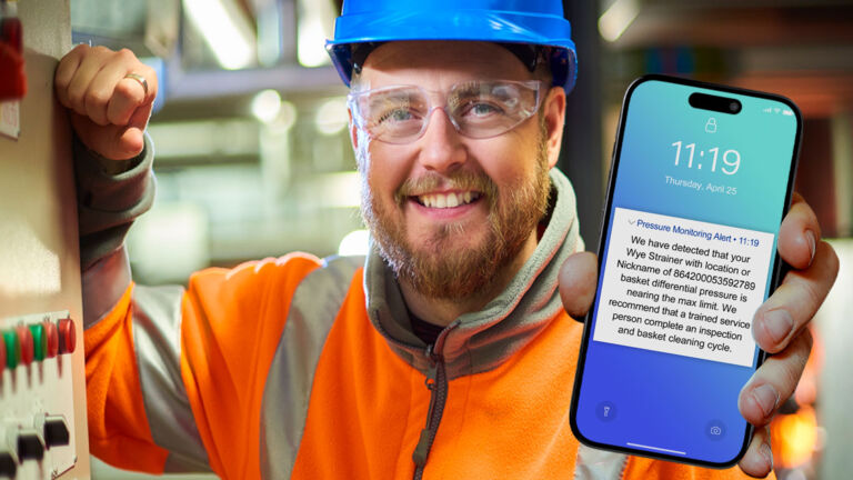 Facility Engineer holding smart phone with service alert at industrial plant
